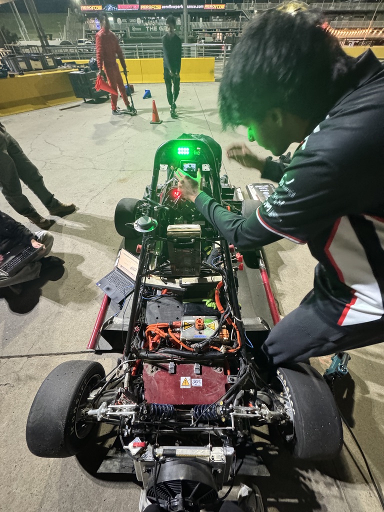 Nathan leaning over the Redback Racing car and checking its GoPro